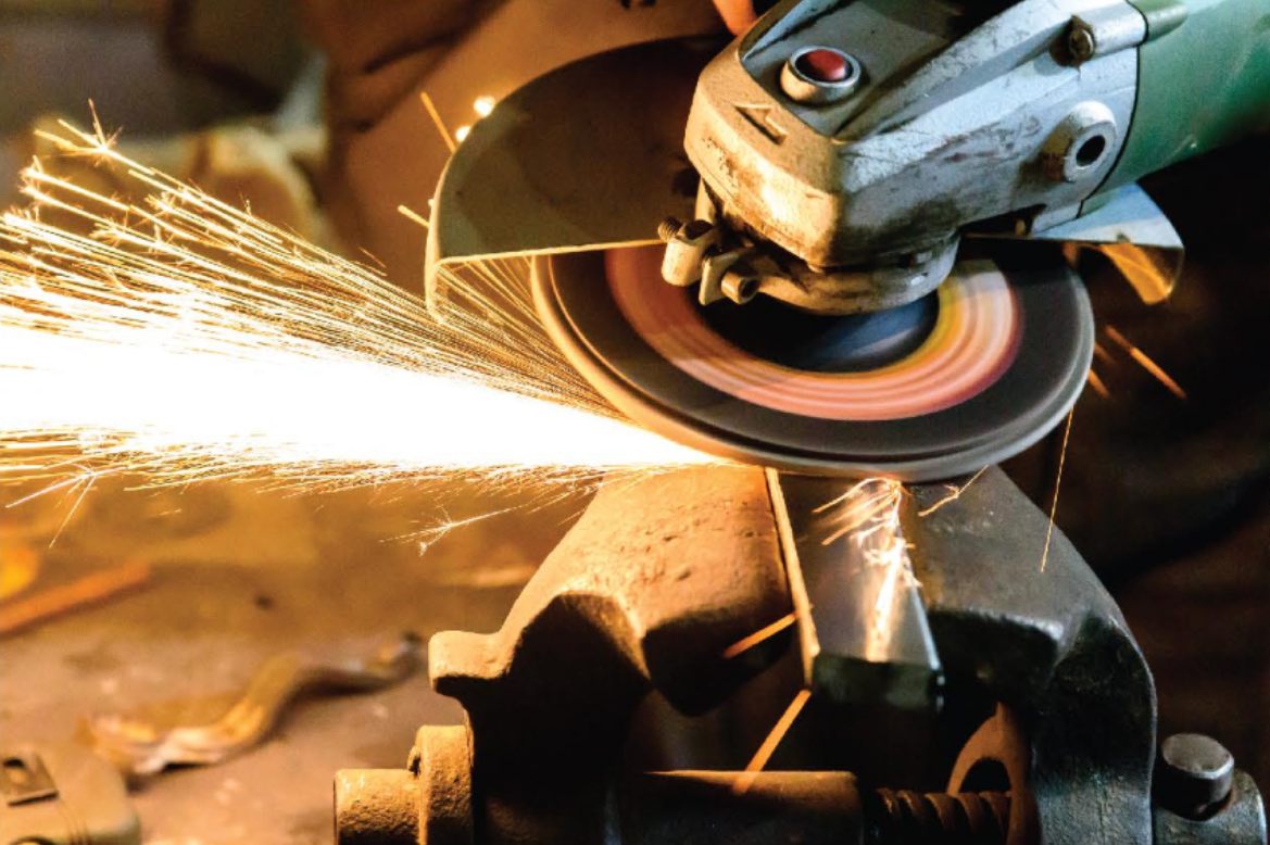 An angle grinder with an abrasive disc throwing sparks off steel