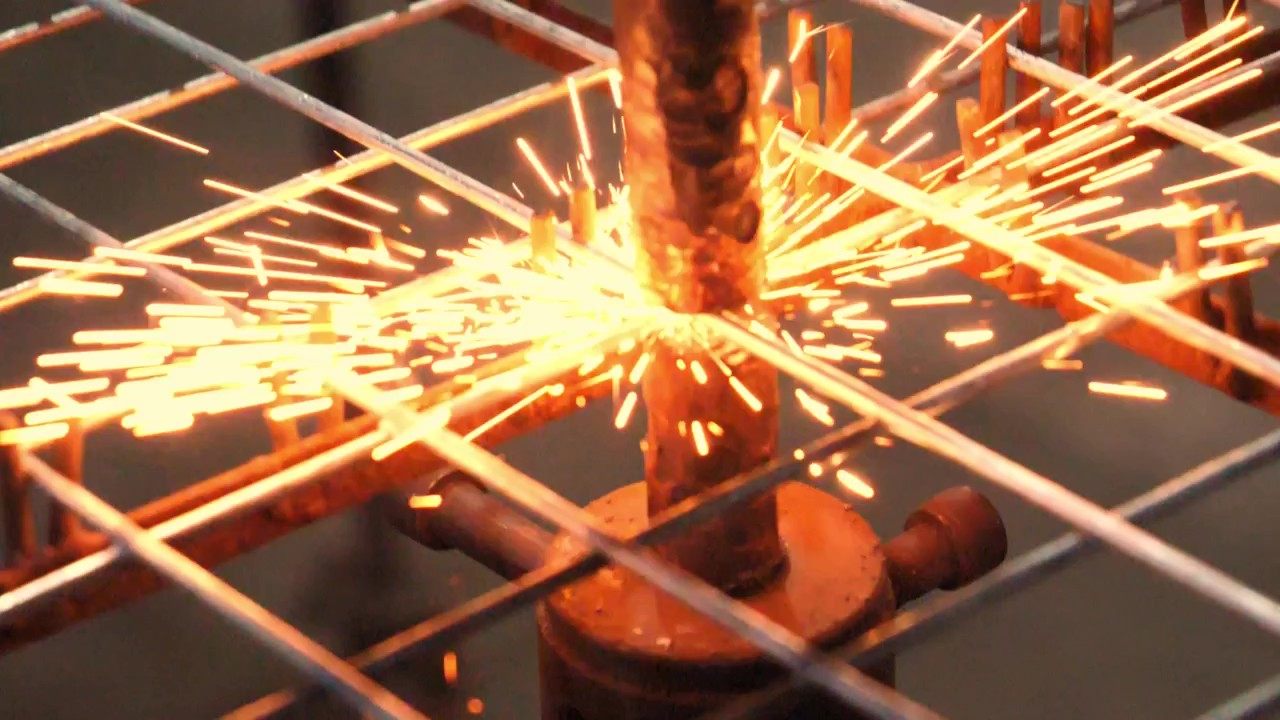 Sparks flying from a welding point on a steel mesh